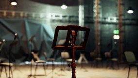 A wooden music stand stands alone in the center of an aged opera house, surrounded by empty chairs. The atmosphere is filled with anticipation for the evenings performance. - Powered by Shutterstock - Get 15% off with code: PIKWIZARD15