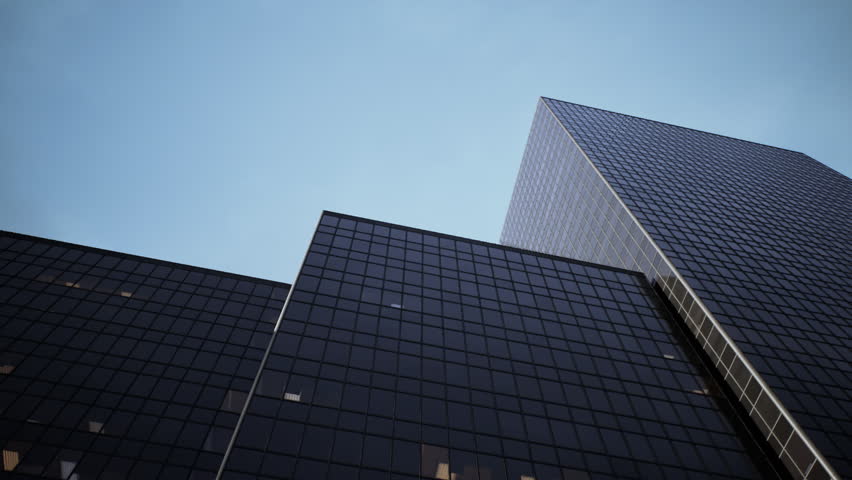 Tall glass buildings tower against a twilight sky, their reflective surfaces gleaming. Ambient light emanates from the windows, hinting at activity within a vibrant urban area.