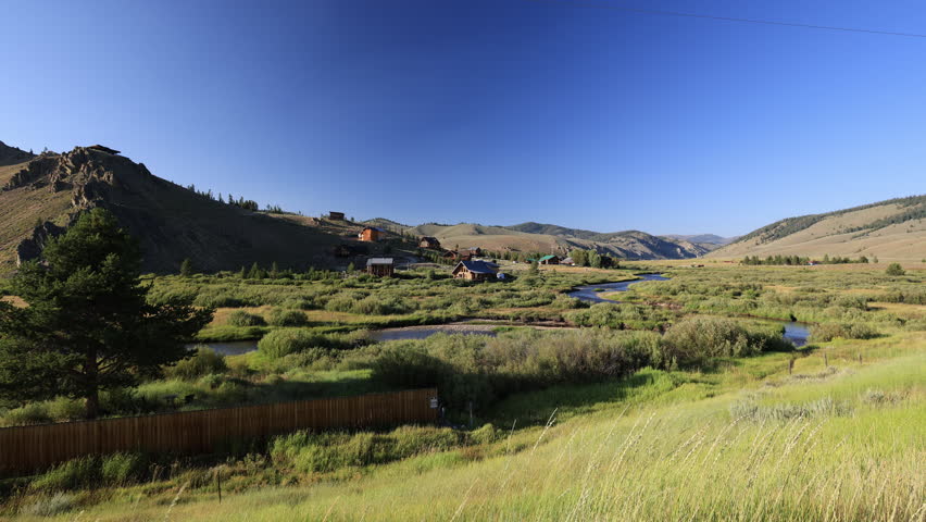A summer afternoon in Stanley, Idaho. Valley Creek flows past cabins nestled in green grass, offering a serene escape surrounded by pristine mountain beauty.
