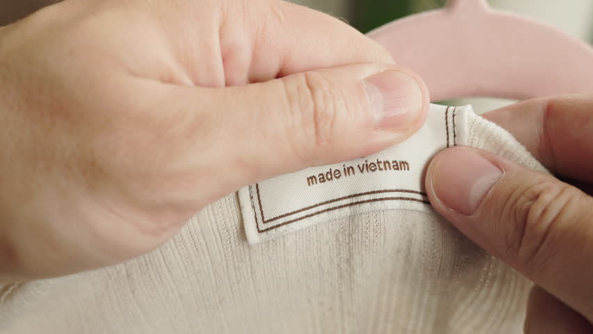 Close-up of hands holding a clothing label with the inscription "Made in Vietnam" 