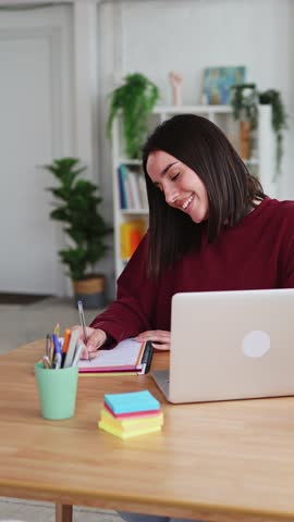 Young woman taking notes while working from home