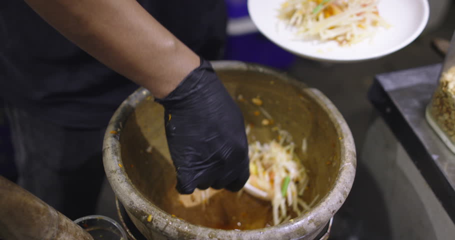 local street stall preparing Som Tum or Thai Papaya Salad, Asian street food, famous traditional dish. Green papaya salad put pickled peanut and Pickled fish. Asian food daily style.