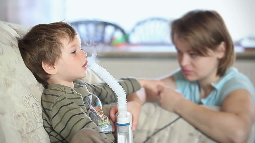 Mother and little boy using nebulizer to inhale medicine