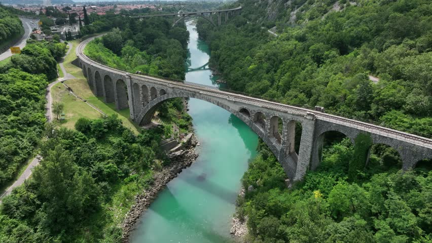 An ascending drone shot of the Solkan Bridge (Solkanski most) over the Soca River near Nova Gorica in western Slovenia on a sunny day