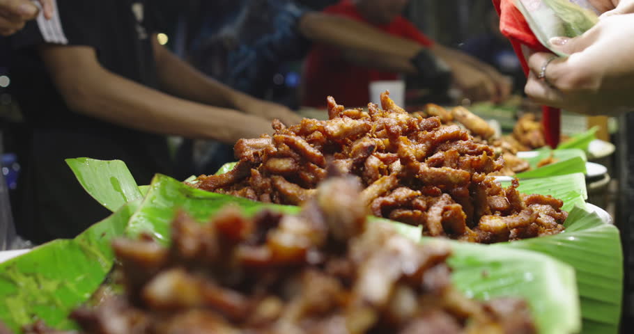 Street food vendor serving fried pork to customer at Thai night market closeup of hands exchanging cash and food traditional urban cuisine Southeast Asia food culture
