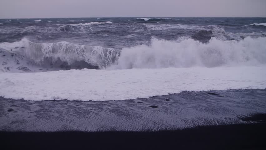 Stormy waves hitting black sand beach in Iceland in slow motion