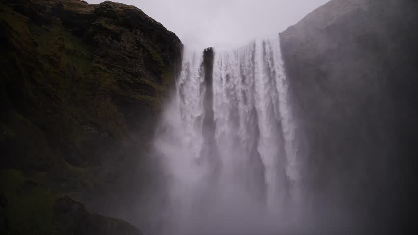 Powerful waterfall flowing between mossy cliffs in Iceland