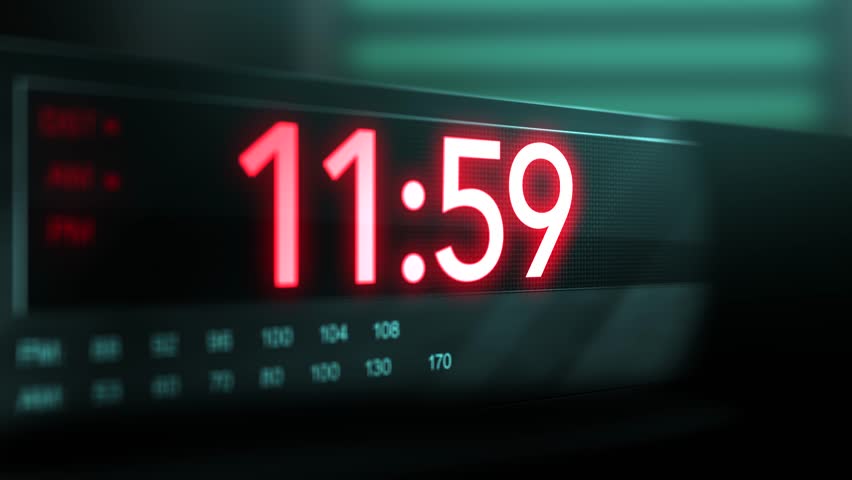 Camera pans across old digital clock as time arrives at 12 AM