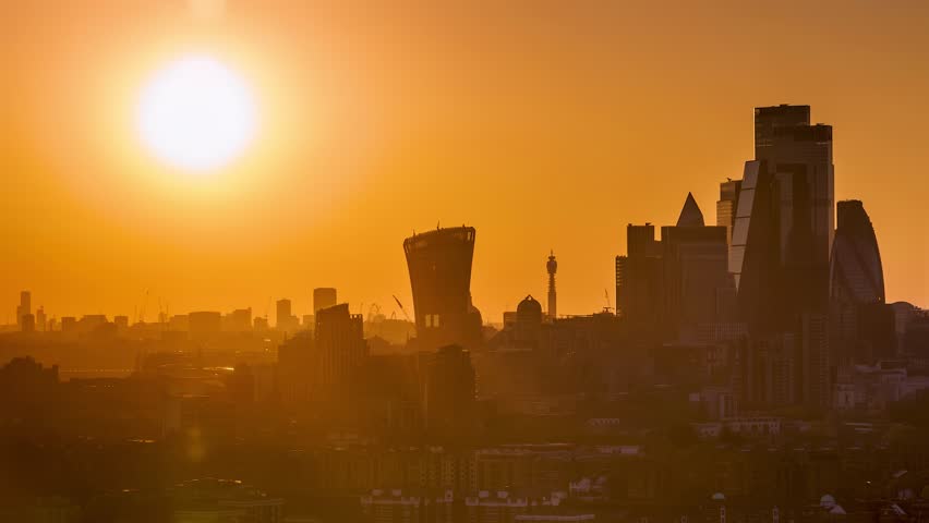 Sunset time lapse view of the skyline at the City of London, England, with the sun setting exactly behind the skyscrapers