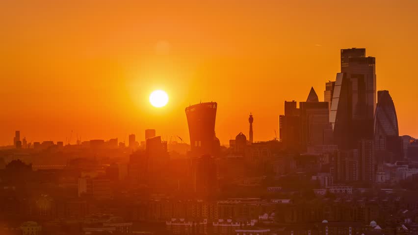Sunset time lapse view of the skyline at the City of London, England, with the sun setting exactly behind the skyscrapers