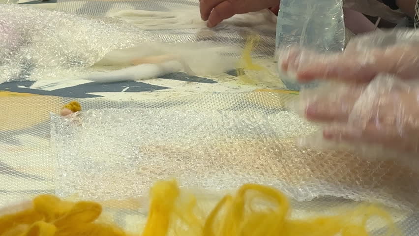 a group of children make a toy from wool, wet felting a blank and squeeze water out of it, the concept of children's master class wet felting