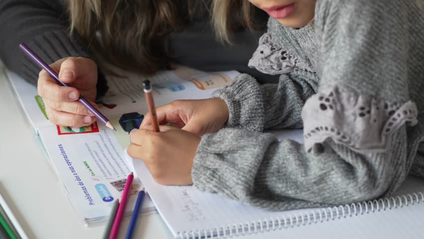 Caucasian mother and African American daughter studying at home, doing homework in cosy white room. Parent teach, child school girl learn knowledge, write exercise read book. Education for children