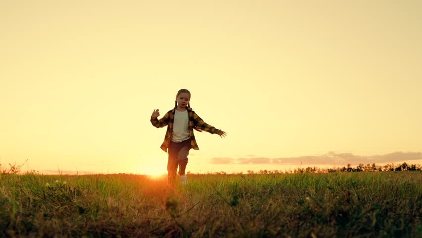 Happy child, girl runs in green grass, raising her hands, joy, smiles laughter. Happy little girl dreams of flying in nature. Children's fantasies. Child running through field of flowers. Happy family