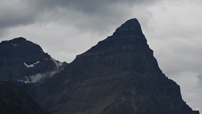 Time lapse of churning storm clouds above rock mountain ridge areas of blue sky