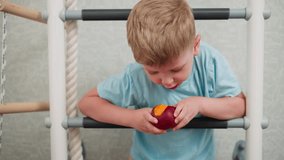 Young boy leans over indoor ladder munching on ripe mango with focus on juicy fruit and playful child moment in bright room showcasing fun and healthy snacking during casual home activity - Powered by Shutterstock - Get 15% off with code: PIKWIZARD15
