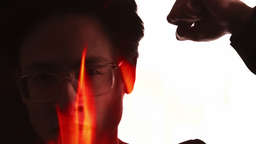Male protest. Burning silhouette. Fire flames double exposure angry mad business man in eyeglasses knocking striking with raised fist isolated on white.