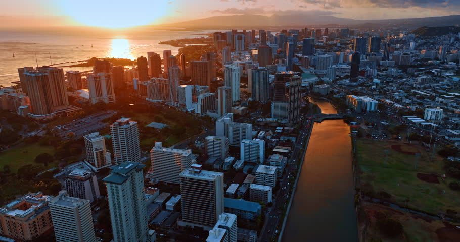 Sunset view of Waikiki, Honolulu, Hawaii, USA. Beautiful soft light reflects in the waterscape of the Pacific Ocean and Ala Wai Canal. Aerial perspective.
