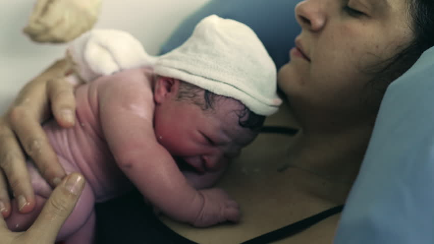 Real life birth moment of newborn baby right seconds after being born, welcoming a new human being into this world