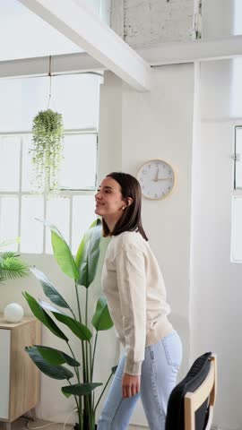 Young woman walking around and sitting on yellow couch in modern living room