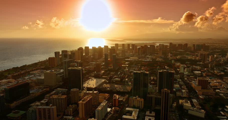 Hot sun lighting the cityscape of Honolulu, Hawaii, USA. Soft warming light covering the scenery. Aerial perspective on the city at sunset.