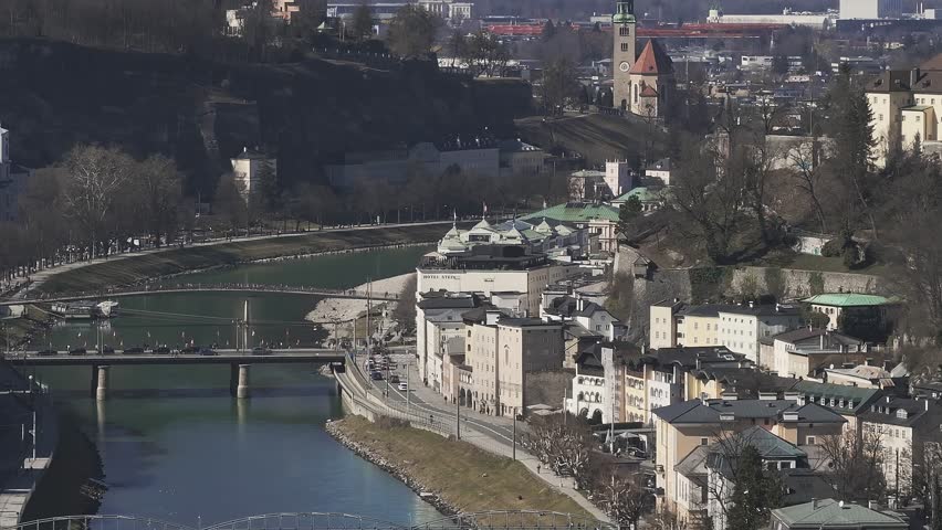 Aerial view of Salzburg, Austria, showing the Salzach River, Salzburg Cathedral, Hohensalzburg Fortress, bridges, and surrounding landscape in slow motion.
