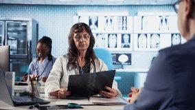 Senior medic gives man patient the bad news of a disease diagnostics, medical consultation with x ray imaging visible on the screen. Healthcare problems and professional research. Camera A. - Powered by Shutterstock - Get 15% off with code: PIKWIZARD15