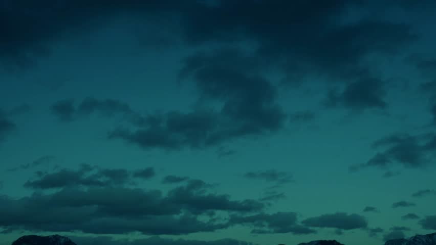 Beautiful blue clouds flying at night, snow mountains.