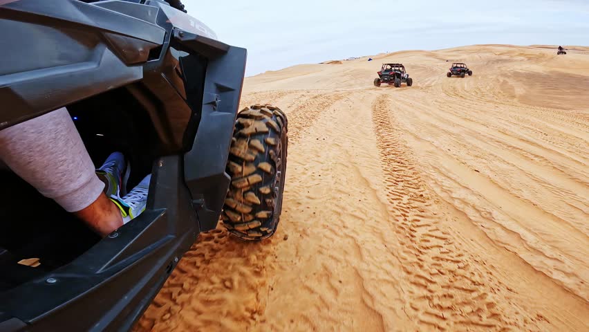 Powerful side angle shows buggy racing through soft sand on Dubai desert trails