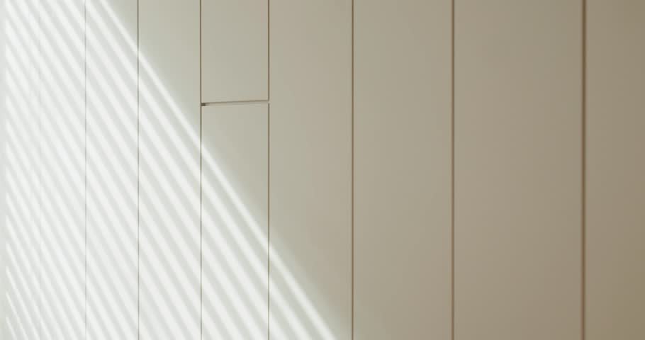 A minimalist interior showcases a wall with subtle light rays and shadows, creating a serene and modern atmosphere. Minimalist Interior Design with Light and Shadows on Wall