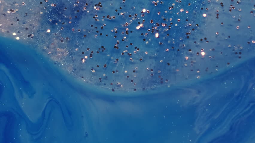 Glitter liquid. Paint mix. Shimmering metal particles gel drop floating in blue artistic water. Abstract defocused moisture background.