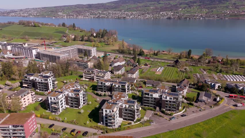 Lake Zurich with luxury penthouse apartment houses with solar panels on roof. Sunny day in swiss district with lake view. Aerial tilt down shot. Wädenswil, Switzerland.