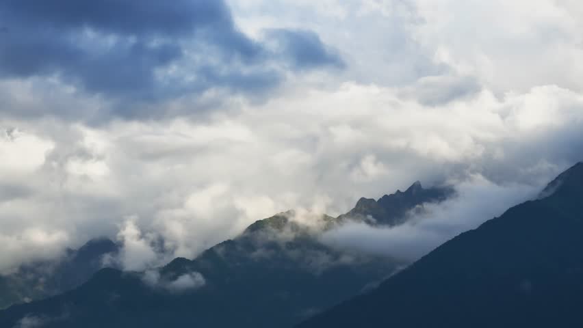 Clouds over the mountains at sunset. Timelapse. Clouds forming and moving over the mountain peaks. Summer landscape. North Ossetia, Caucasus, Russia.