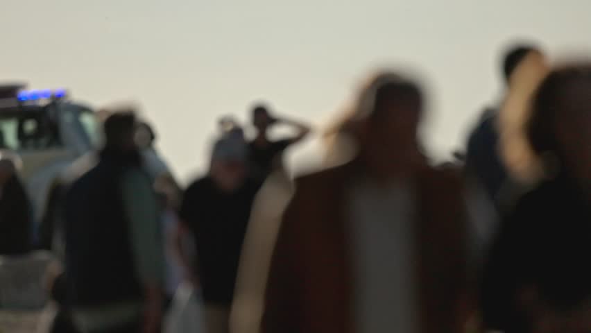Blurred crowd gathering near emergency vehicle with flashing lights