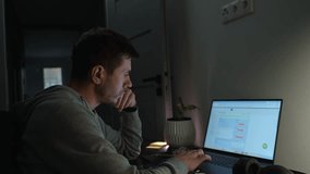 Concentrated freelancer working late at home office. Focused man in hoodie writes notes while working on laptop. Concept of night work - Powered by Shutterstock - Get 15% off with code: PIKWIZARD15