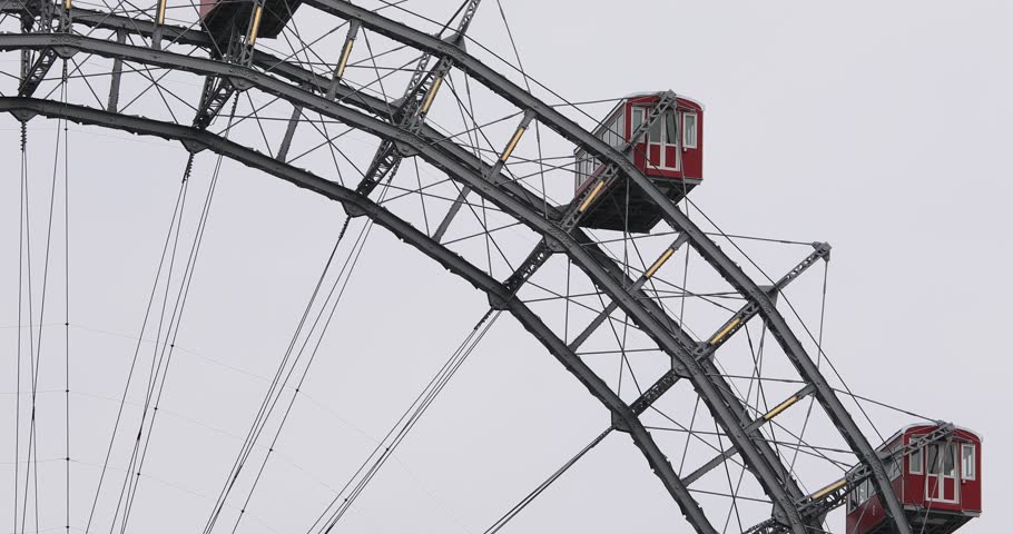 The iconic Vienna Ferris Wheel in Prater park stands still with its red gondolas and steel frame under an overcast sky. A historic landmark built in 1897 in Vienna