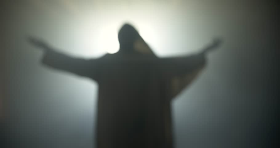 Silhouette of resurrection of Jesus Christ inside the tomb, in bright light, raising his hands in dramatic, cinematic slow motion. Perfect for Easter resurrection visual.
