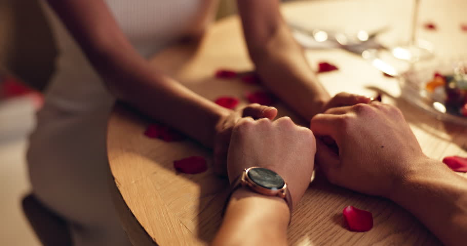 Couple, holding hands and love on date at restaurant for roses, romantic and valentines day celebration. Closeup, people and trust of anniversary dinner, relationship commitment and partner affection