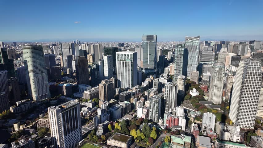 Cityscape of Tokyo's Minato Ward showcasing modern skyscrapers against a clear blue sky. pan left