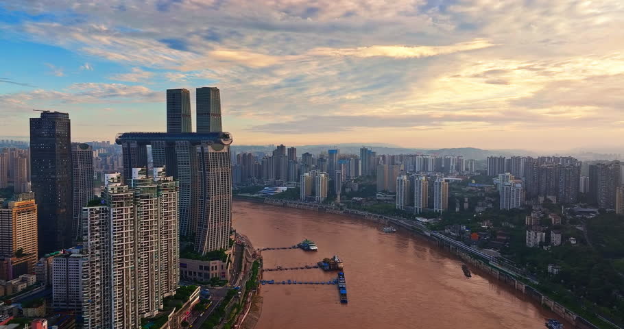 Aerial view of building complex and cityscape situated at the confluence of two rivers at sunset in Chongqing, China.