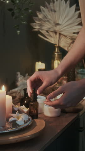 Vertical shot of unrecognizable masseuse applying oil to her hands before massage session in spa