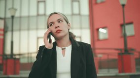 Lady in professional outfit appears tired while on phone call in modern urban setting, people blur in distant background, showing signs of exhaustion, stress, and emotional fatigue during conversation - Powered by Shutterstock - Get 15% off with code: PIKWIZARD15
