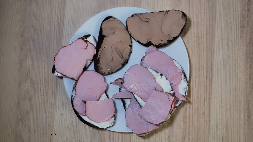 Plate of rustic open sandwiches with dark bread, ham, liver spread, beef pate