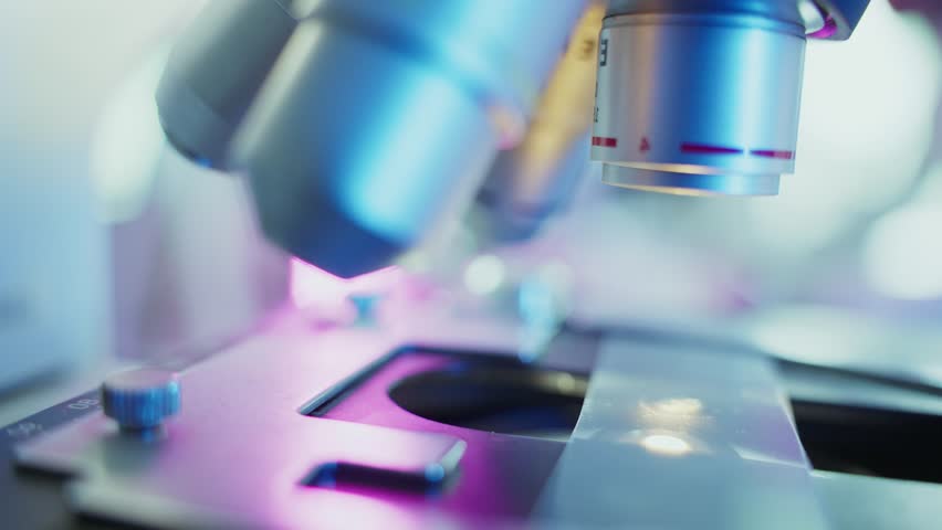 Laboratory technician meticulously adjusting microscope lenses, illuminating specimens with focused beams of light, preparing for detailed scientific observation
