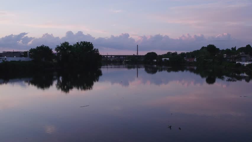 Aerial shot of a peaceful riverbank at dusk with colorful twilight skies mirrored in the water near New York City.