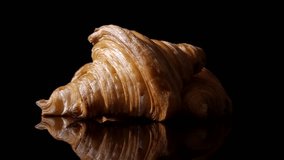 Three croissants rotating counter clockwise on a black reflective surface, strong mirror reflection, dark background emphasizing golden flaky pastry texture. Croissant. - Powered by Shutterstock - Get 15% off with code: PIKWIZARD15