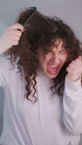 Curly haired woman battles morning knots desperately trying to detangle her hair showing frustration and real life beauty routine