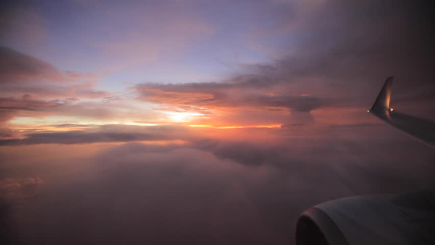 
Aerial view of sunrise through airliner window in the morning. Aerial view of Cloudscape in dawn through plane 