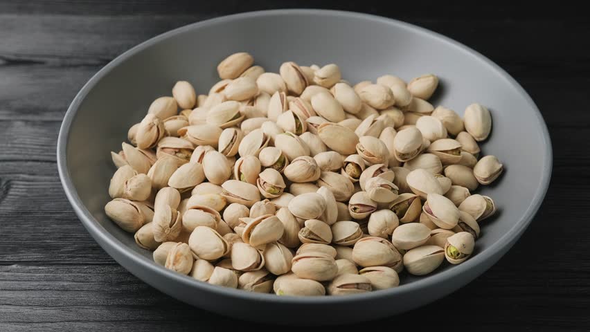 Man hand taking salted roasted pistachios in their shells, a healthy snack