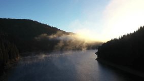  Slow motion aerial view of a misty lake. Dawn dark lights during sunrise, cold weather. Flying over clouds in the mountains - Powered by Shutterstock - Get 15% off with code: PIKWIZARD15