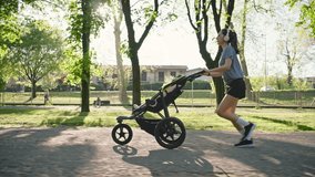 Slowmotion of A young sporty woman runs in the park with her son in the running board. Mom is happy to do sports in the park with her newborn baby on a sunny day. Concept of power, fitness, family - Powered by Shutterstock - Get 15% off with code: PIKWIZARD15